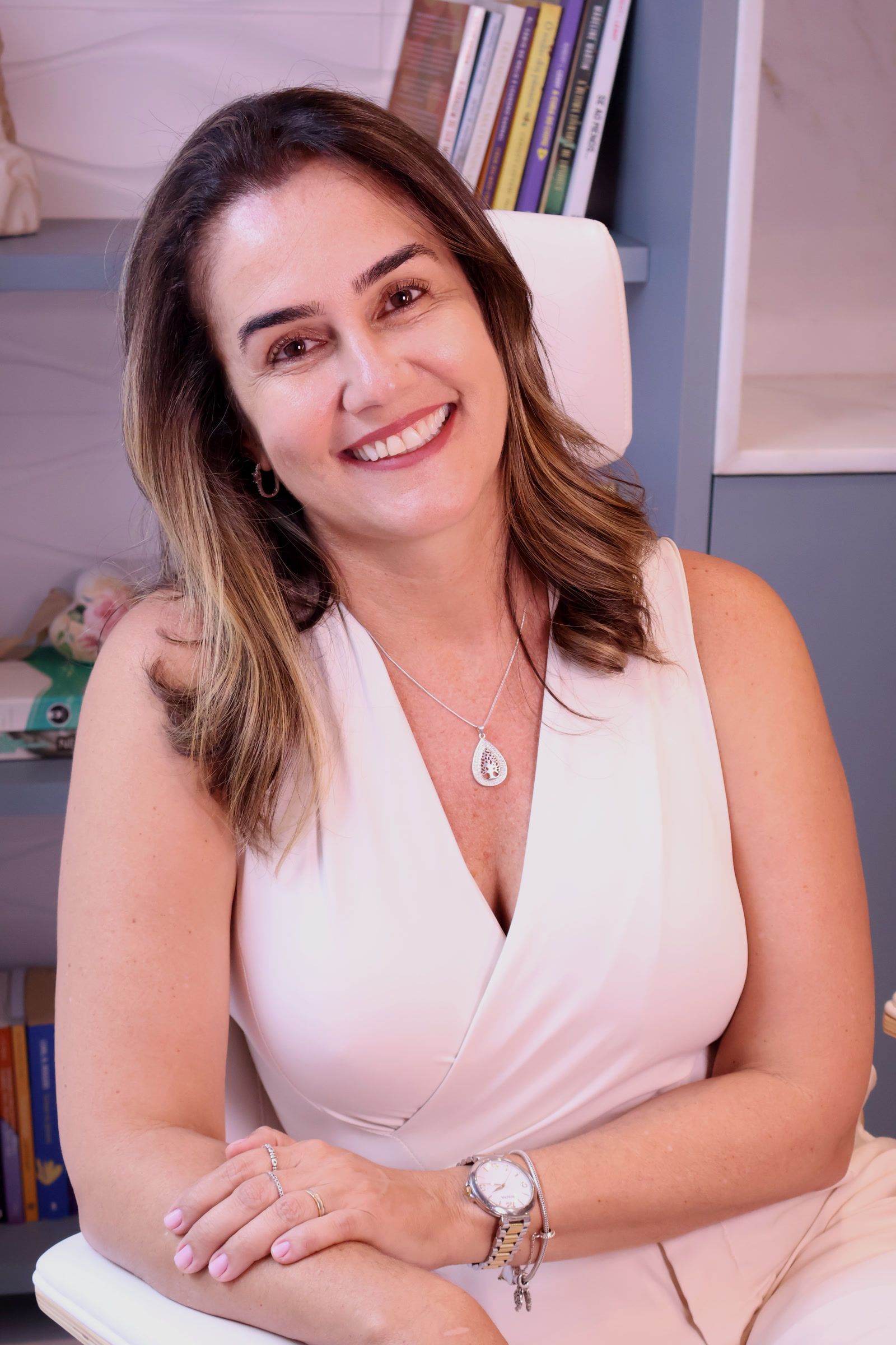 Núbia Paixão sorrindo, sentada na poltrona do consultório.